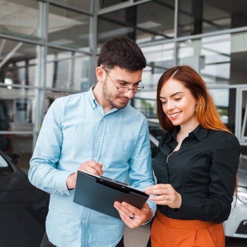Car showroom seller gives papers to a client